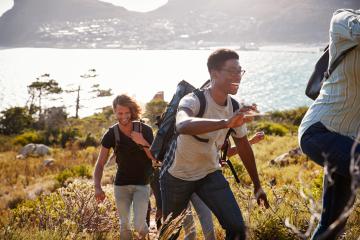 happy-young-adult-friends-hiking-uphill- 